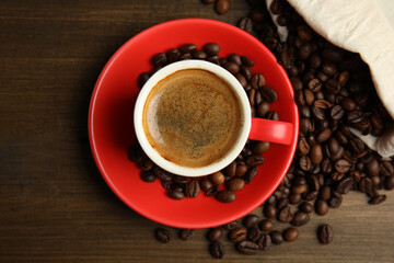 Cup of tasty coffee and beans on wooden table, flat lay