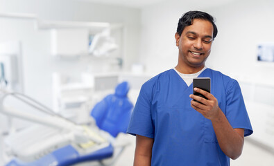 medicine, stomatology and technology concept - happy smiling indian doctor or male dentist in blue...