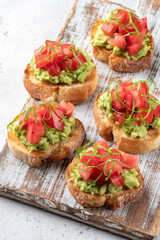 avocado and tomato crostini. Bruschetta toast with mashed avocado