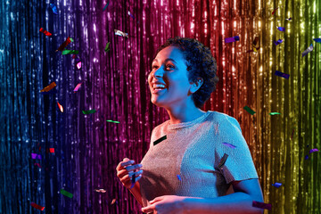 leisure, party and nightlife concept - happy smiling young african american woman under confetti...