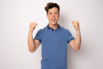 Happy winner. Happy young handsome man gesturing and keeping mouth open while standing against white background