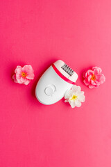 Top view of white epilator with flowers for hair removal