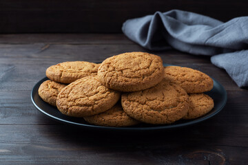 Natural homemade oatmeal cookies on a plate, dark wooden background, copy space.