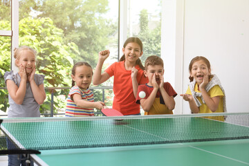 Cute happy children playing ping pong indoors