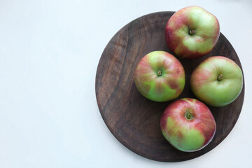 Red apples on a wooden plate against white background. Apples as a background. Flat lay, top view, copy space