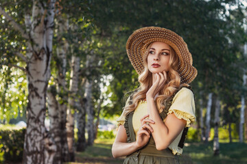 Portrait of a woman with blonde hair in retro clothes in a park or garden