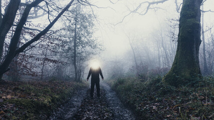 An alien entity with lights glowing from it's head in an eerie forest. On a mysterious foggy, winters day - obrazy, fototapety, plakaty