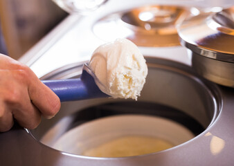 scoop of creamy ice cream in spoon from the refrigerator container