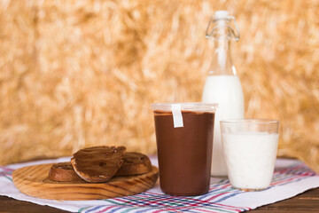 hazelnut cream and milk in a bottle and sun takane on the table against a background of hay