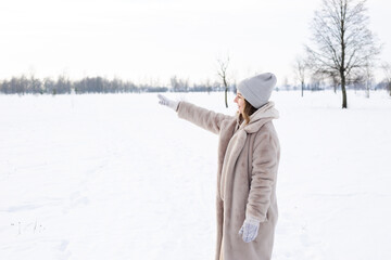 Young girl in beige clothes, fur coat made of artificial fur walks in winter