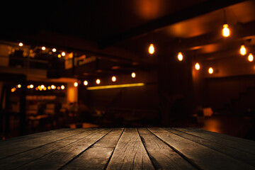 image of wooden table in front of abstract blurred background recreating lights of restaurant cafe