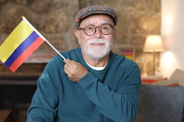 Senior man holding the Colombian flag at home
