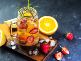 Infused detox water with orange, strawberry, lemon and rosemary. Summer refreshing lemonade, colorful bright background