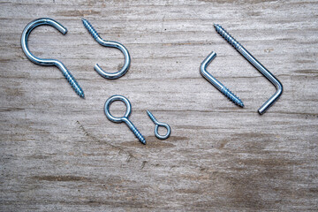 Set of screws and hooks for easy fixing on a wooden background. View from above. Space for lettering and design