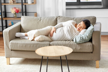 pregnancy, rest, people and expectation concept - happy smiling pregnant asian woman sleeping on sofa at home