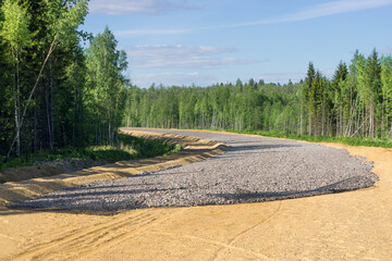 Highway road construction, gravel laying over sandy mound