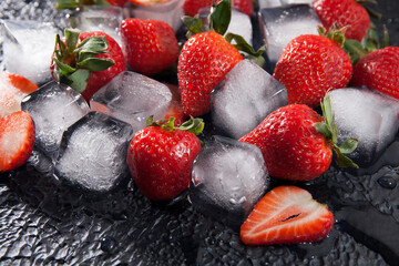 Fresh red strawberries with ice cubes on dark textured background