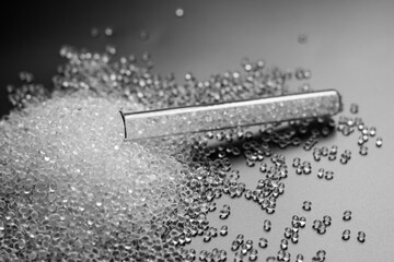 white granules of rubber and polypropylene on a black background in a chemical test tube. Plastics...