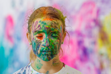 The girl's face is painted with bright colors at the festival. A creative holiday for people. Contemporary art, performance. 