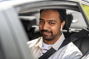 transport, people and technology concept - smiling indian man or driver with wireless earphones or...