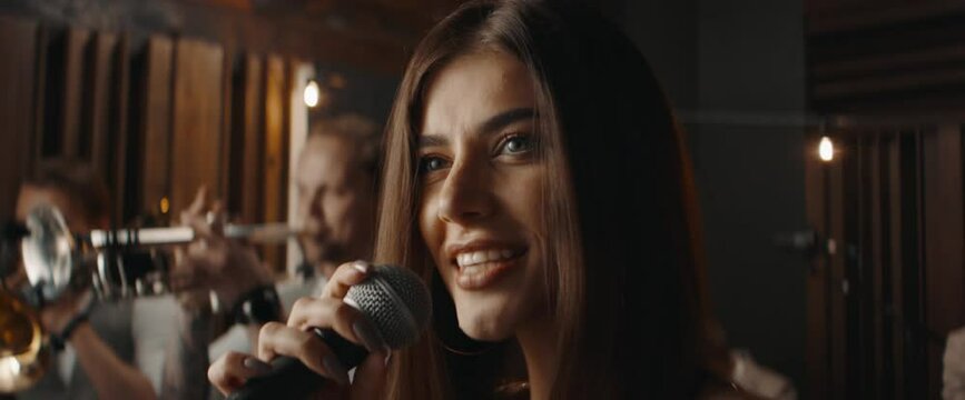 HANDHELD CU Portrait of female singing during jazz band rehearsal in recording studio. Shot with 2x anamorphic lens
