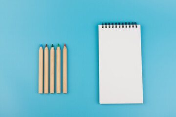 Blank paper and a colorful pencil on a blue background