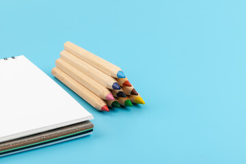 Fototapeta premium Blank paper and a colorful pencil on a blue background