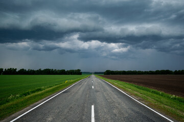A road leading into the distance, through the sky in thunderclouds.