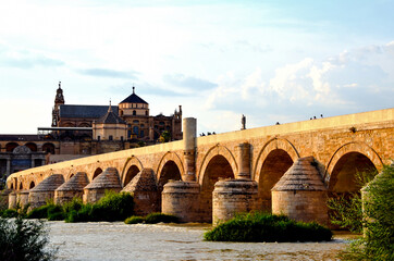 Fototapeta premium Roman bridge over the Guadalquivir River and in the background the Great Mosque of Cordoba or Mosque-Cathedral of Cordoba, Andalusia, Spain