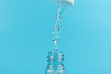 face serum drop with bottle on blue background.