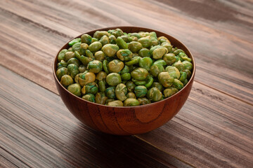 Salted green peas in wooden bowl on the table, Healthy snack, Vegetarian food.