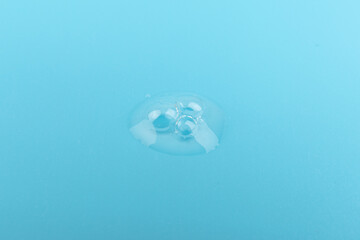 face serum drop in close up on blue background.