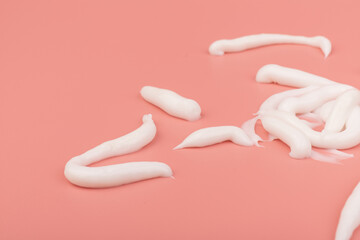 White cosmetic cream smear isolated on pink background. Skincare product creamy texture.