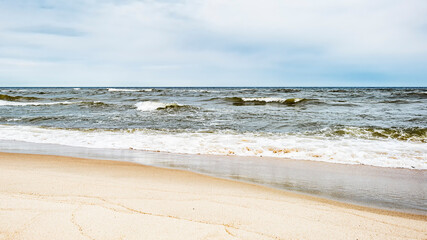 Sea waves on the beach and overcast sky - obrazy, fototapety, plakaty