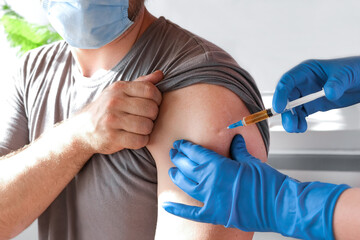 Hands of doctor injecting coronavirus covid-19 vaccine in vaccine syringe to arm muscle of...