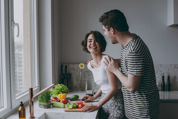 Young side view fun happy couple two laughing woman man 20s in casual t-shirt clothes prepare...