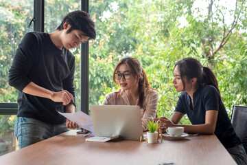 Group of young Asian business people sitting at work brainstorming meeting together at the office.