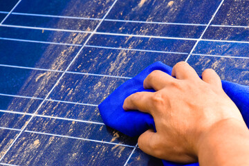 Solar cell panel covered by dust is being cleaned by hand holding blue fabric, soft and selective...