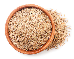 Unpeeled oats in a wooden plate on a white background, isolated. Top view