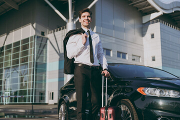 Fototapeta na wymiar Bottom view smiling young traveler businessman young man in black dinner suit going walk outside at international airport terminal with suitcase near car booking taxi Air flight business trip concept