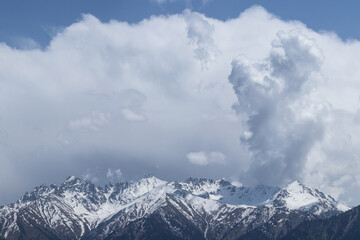 Fototapeta na wymiar Huge clouds over mountain snowy peaks