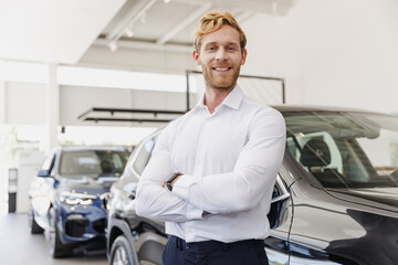 Man successful happy customer male buyer client wear white shirt hold hand crossed folded choose auto want buy new car automobile in showroom vehicle dealership store motor show indoor. Sales concept
