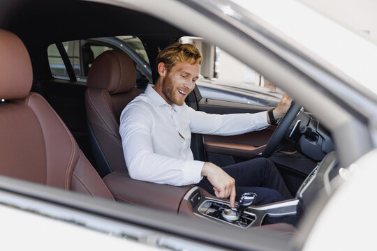 Man fun customer buyer male client in classic suit shirt sit in car salon turn on music drive choose auto want buy new automobile in showroom vehicle dealership store motor show indoor Sales concept