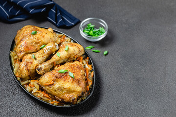 Oven roasted chicken with vegetables on dark background in cast iron skillet. Space for text.
