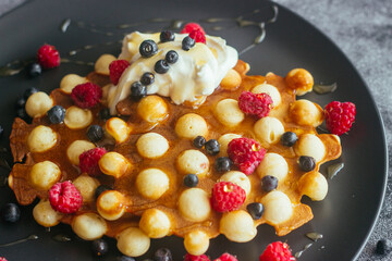 Delicious hong kong waffles. Waffles with raspberries, blueberries, sour cream and honey. Waffles on the table 