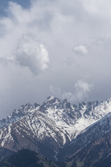 Clouds of different sizes over mountain snowy peaks