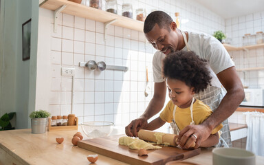 African American Father and son baking at home together. Child enjoying helping Dad. Brazilian family in the kitchen.
