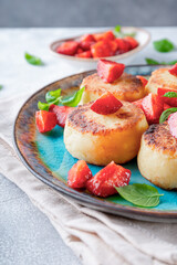  Cottage cheese pancakes with strawberries and mint on a blue plate close up vertical photo