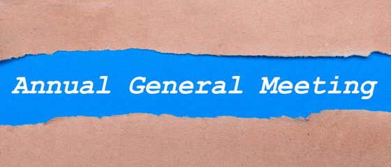 A strip of blue paper with the inscription Annual General Meeting between the brown paper. View from above