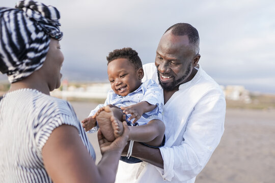 African American Parents Having Fun With Toddler In Summer Vacation On The Beach - Family Love